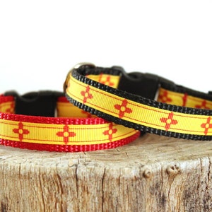 May include: Two dog collars with a yellow and red Southwestern design. The collars are made of black webbing with a yellow and red ribbon with a red geometric pattern.