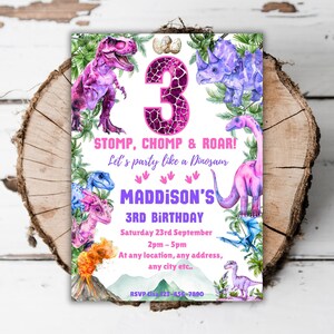 Puede incluir: Una invitación de fiesta de cumpleaños de dinosaurio rosa y morado con un gran número 3 en el centro. La invitación dice "STOMP, CHOMP & ROAR! Let's party like a Dinosaur" y "MADDISON'S 3RD BIRTHDAY".