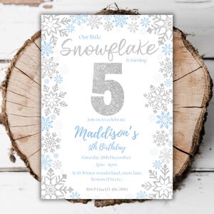Puede incluir: Una invitación blanca con un diseño de copo de nieve de purpurina plateada. La invitación es para una fiesta de cumpleaños número 5 para Maddison. El texto de la invitación dice: "Nuestro pequeño copo de nieve cumple 5 años. Únase a nosotros para celebrar el 5º cumpleaños de Maddison. Sábado 28 de diciembre de 2 pm a 6 pm. En 45 Winter wonderland, snow lane, Boston 1234 etc.. RSVP Lisa 123-456-7890"