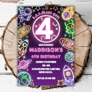 May include: A purple and black birthday invitation with neon-style space-themed graphics. The invitation features a large number 4, rockets, planets, and the text "MADDISON'S 4TH BIRTHDAY". The invitation also includes the text "3...2...1...BLAST OFF!"