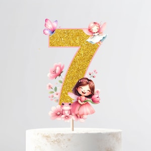 Op de afbeelding: Gouden glitter cijfer zeven taarttopper met roze bloemen, een kikker en twee feeën. De feeën dragen roze jurken en hebben roze vleugels.