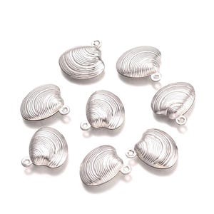 May include: A collection of eight silver-colored seashell charms. Each charm has a detailed, ridged surface and a small loop for attaching to jewelry or other crafts. The charms are arranged on a white background.