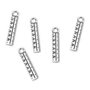 May include: Five silver-toned metal ruler charms with a loop at the top. Each charm has a ruler with numbers 1 through 6.