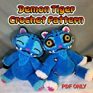 K&ouml;nnte beinhalten: Zwei blaue geh&auml;kelte Tiger-Stofftiere mit wei&szlig;en Akzenten, rosa Nasen und schwarzen Streifen. Der linke Tiger hat geschlossene Augen, der rechte hat gro&szlig;e gelbe Augen. Der Text lautet Demon Tiger Crochet Pattern und unten PDF ONLY.