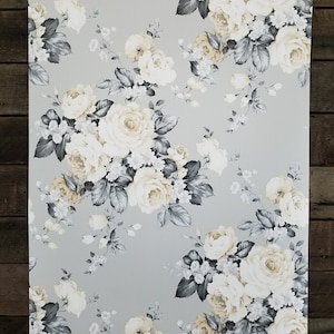 May include: A gray and white floral wallpaper with a repeating pattern of large white roses with yellow centers and gray leaves.