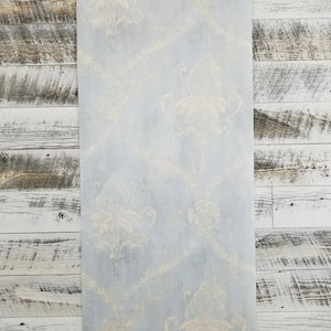May include: A light blue wallpaper with a subtle, faded, white floral pattern. The wallpaper has a distressed, vintage look.