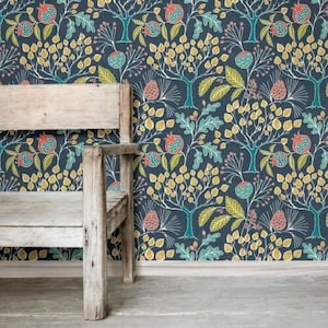 May include: A rustic wooden bench stands before a wall adorned with patterned wallpaper. The wallpaper showcases a repeating design of stylized trees, pomegranates, and leaves in teal, yellow, and coral on a dark blue backdrop. The bench is made of aged wood.