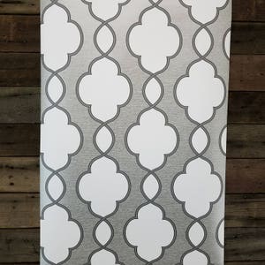 May include: Gray and white wallpaper with a repeating geometric pattern. The pattern features a series of interlocking quatrefoils.