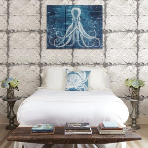 May include: A white bed with white bedding and a blue pillow featuring a white octopus design. The headboard is a white tiled wall with a blue and white octopus print hanging above the bed.