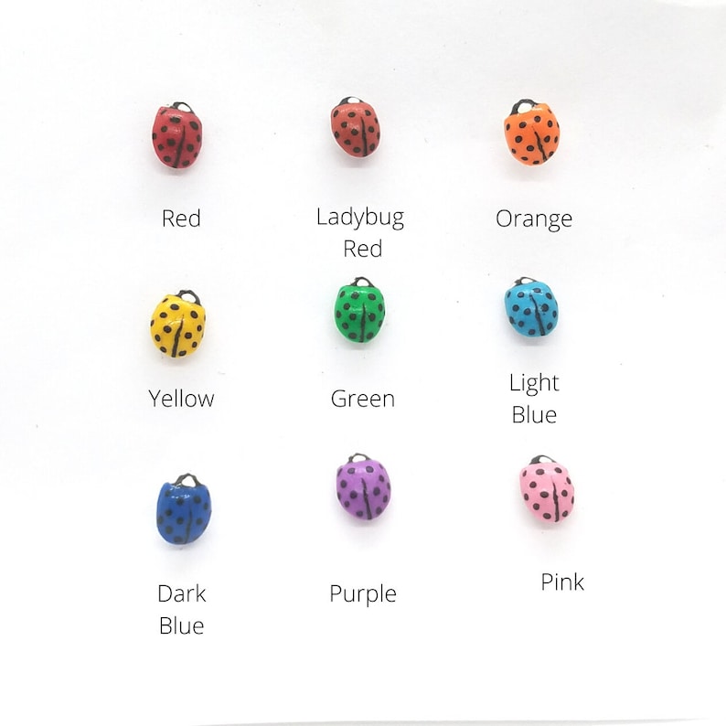 May include: Nine ladybug figurines in different colors: red, ladybug red, orange, yellow, green, light blue, dark blue, purple, and pink. Each ladybug has black spots.