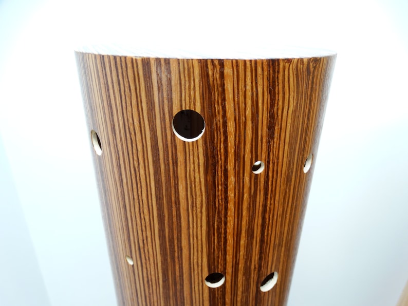 May include: A brown wooden cylindrical lamp base with a white top and multiple circular cutouts.