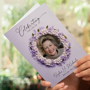 Op de afbeelding: Een lavendelkleurige herdenkingskaart met een foto van een lachende vrouw omringd door een bloemenkrans. De kaart leest "Celebrating the Life of Sophia Y. Michaels" met data 17 juni 1992 - 12 mei 20--. De tekst "Design it for... me, us, them..." is ook zichtbaar.