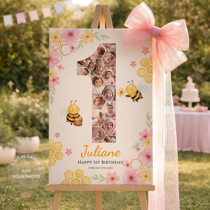 May include: A personalized first birthday sign on an easel. The sign features a large number one with a collage of baby photos. It is decorated with pink and yellow flowers, bees, and honeycomb patterns. The sign reads "Juliane Happy 1st Birthday". A large pink bow is attached.