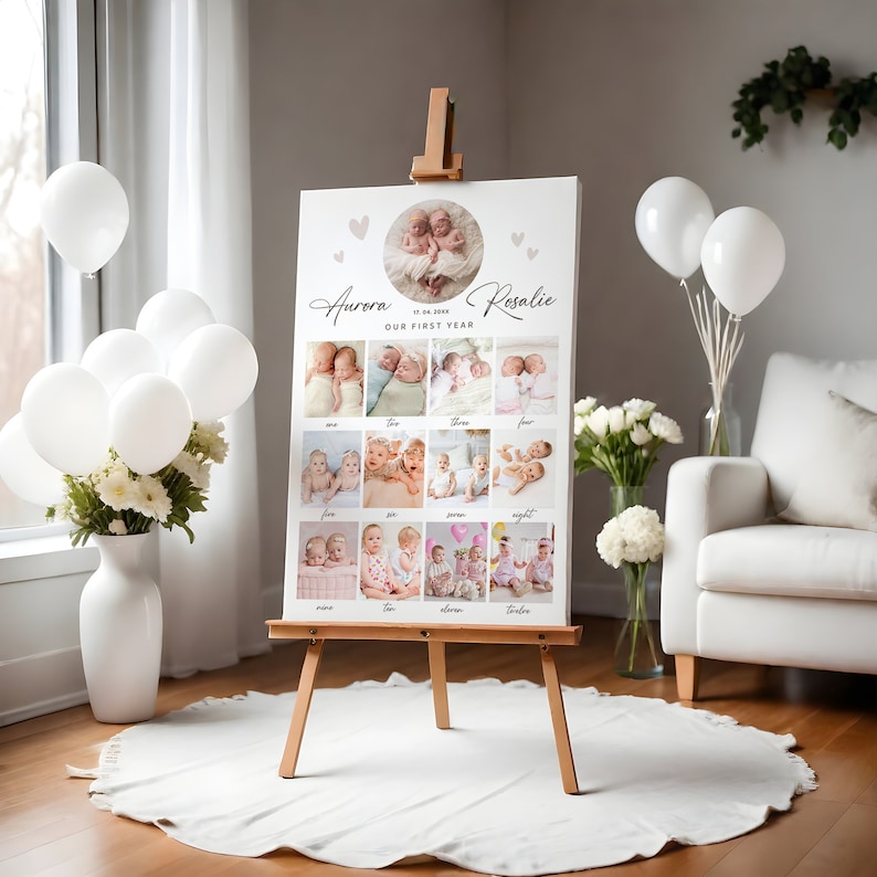 Peut inclure: Un tableau blanc avec un collage de photos de jumelles. Le tableau est sur un chevalet et porte le texte "Aurora & Rosalie Notre premi&egrave;re ann&eacute;e" avec une date et des c&oelig;urs.