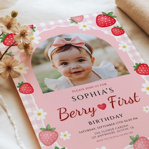 Könnte beinhalten: Eine Geburtstagseinladungskarte mit rosa Vichy-Karo-Rand, roten Erdbeeren und weißen Gänseblümchen. In der Mitte ist ein Foto eines Kindes mit rosa Schleifen-Stirnband zu sehen. Text: PLEASE JOIN US FOR SOPHIA'S Berry First BIRTHDAY.