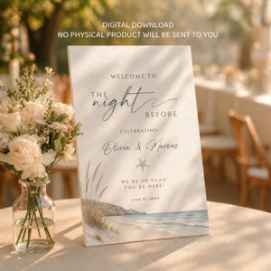 May include: A welcome sign for a wedding or event. The sign reads "Welcome to the Night Before" and celebrates Olivia & Marcus. The sign has a beach scene at the bottom and the text "We're so glad you're here!" and "June 21, 20XX".