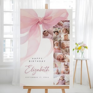 May include: A personalized birthday sign featuring a large pink bow and a collage of baby photos. The sign includes the text "Happy Birthday" and the name "Elizabeth" with the date "September 17, 20XX". The sign is displayed on a wooden easel.