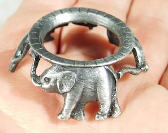 May include: A silver metal elephant figurine with a round ring on top. The elephant is standing on all four legs and has a trunk that is curled up.