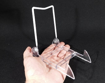 以下が含まれることがあります： 白い金属製の支えが付いた透明なプラスチック製のディスプレイスタンド。スタンドは、プレートやその他の平らな物を置くように設計されています。