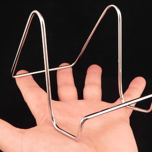 May include: A silver metal display stand with a triangular shape. The stand is made of thin wire and has a simple design.