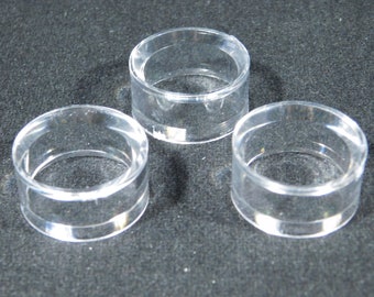 May include: Three clear plastic ring holders. The holders are cylindrical and have a smooth, polished finish.