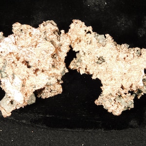 May include: Two pieces of raw copper ore with a rough, textured surface and a metallic, reddish-brown color. The copper ore has a porous appearance with small holes and some areas of gray and green mineral inclusions.