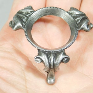 May include: Silver metal orb stand with three ornate legs. The stand is designed to hold a sphere or ball.