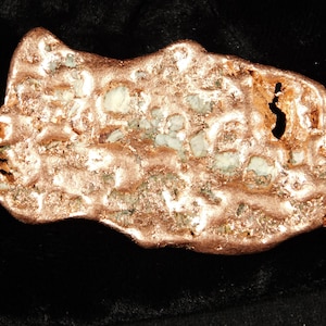 May include: A copper nugget with a rough, textured surface. The nugget has a mix of copper and other minerals, with a few small holes. The colors are primarily copper and white, with hints of green.