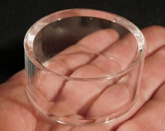 May include: A clear glass cylinder with a smooth, rounded rim. The cylinder has a slightly textured surface.