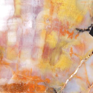May include: Abstract close-up of a polished stone surface. The stone features a blend of colors, including yellow, orange, white, and hints of purple. The surface has a natural, textured appearance with visible veins and patterns.
