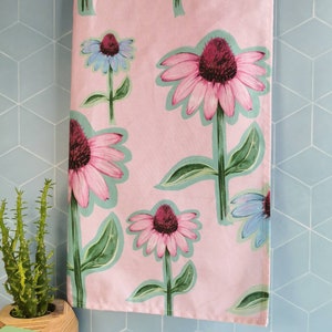 May include: Pink kitchen towel with a floral pattern of purple and pink coneflowers with green leaves.
