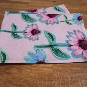 May include: Pink tea towels with a floral pattern of pink and blue flowers with green leaves.