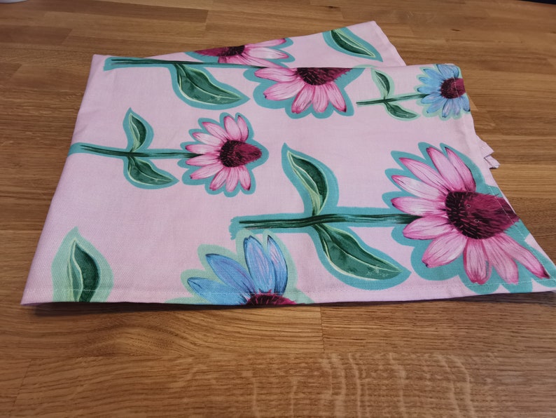 May include: Pink tea towels with a floral pattern of pink and blue flowers with green leaves.