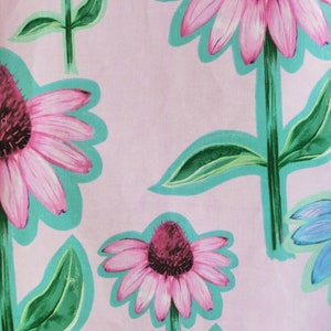 May include: Pink and green floral print fabric with a repeating pattern of pink flowers with dark centers and green leaves. The background is a light pink.