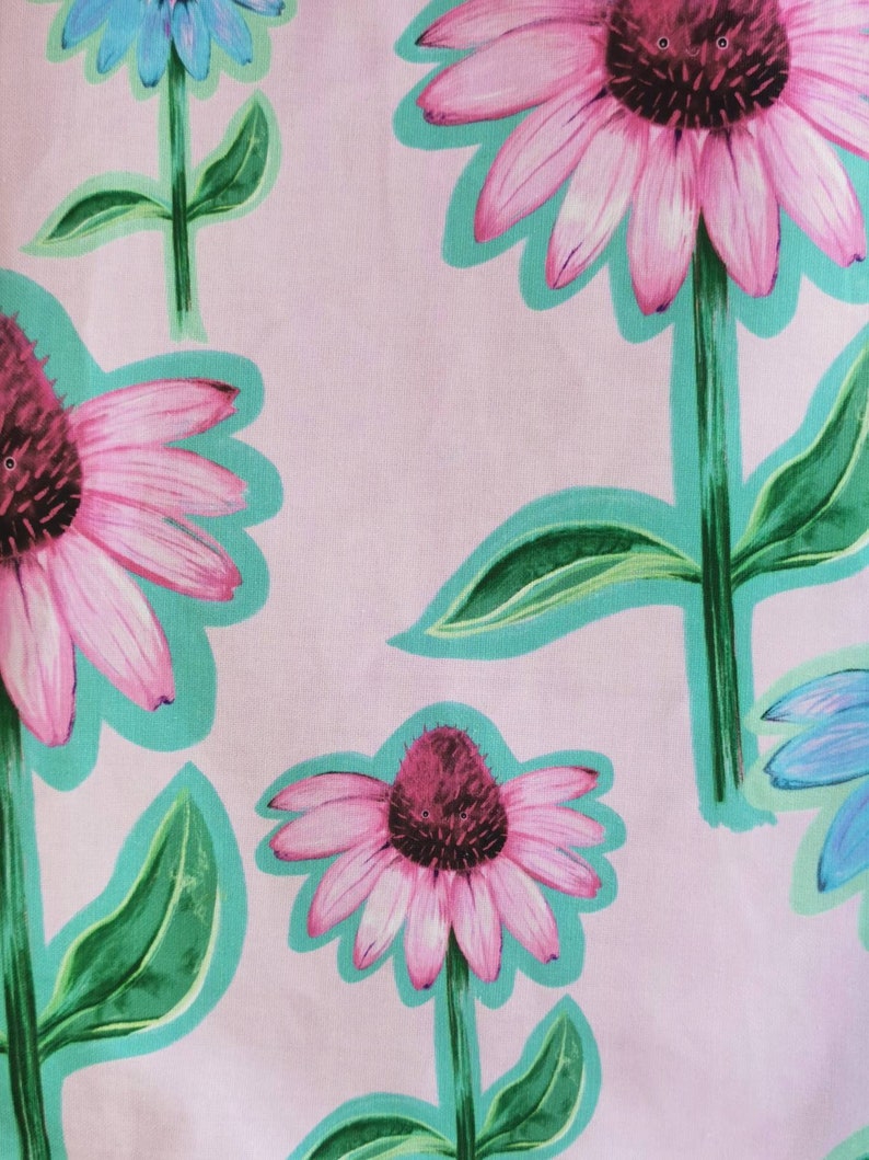 May include: Pink and green floral print fabric with a repeating pattern of pink flowers with dark centers and green leaves. The background is a light pink.