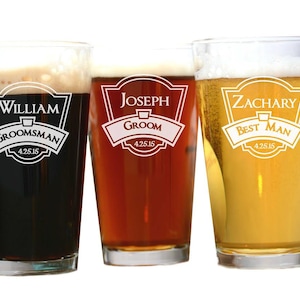 May include: Three personalized pint glasses filled with beer. Each glass has a different beer color and a white label with a name and role: William, Groomsman; Joseph, Groom; and Zachary, Best Man. The date 4.25.15 is also included.