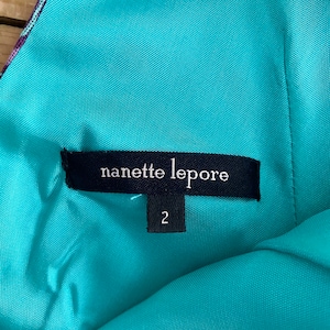 Peut inclure: Un tissu turquoise avec une &eacute;tiquette noire qui indique "nanette lepore" et une &eacute;tiquette de taille indiquant "2".