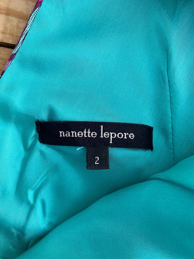 Peut inclure: Un tissu turquoise avec une &eacute;tiquette noire qui indique "nanette lepore" et une &eacute;tiquette de taille indiquant "2".