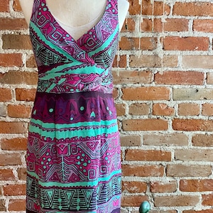 Peut inclure: Une robe sans manches avec un d&eacute;collet&eacute; en V et un motif g&eacute;om&eacute;trique color&eacute; dans des tons de rose, violet, vert et marron. La robe a un corsage ajust&eacute; et une jupe fluide.