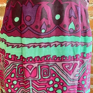 Peut inclure: Gros plan sur une jupe avec un motif g&eacute;om&eacute;trique color&eacute;. La jupe est en tissu tiss&eacute; et pr&eacute;sente une palette de couleurs rose, verte et violette.