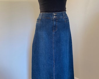 May include: A long denim skirt with a button closure and a straight silhouette. The skirt is a dark blue wash and has a classic style.