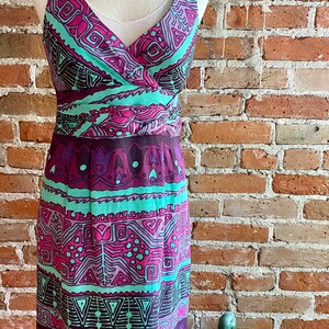 Peut inclure: Une robe sans manches avec un d&eacute;collet&eacute; en V et un motif g&eacute;om&eacute;trique color&eacute; dans des tons de violet, rose, vert et marron. La robe a un corsage ajust&eacute; et une jupe fluide.