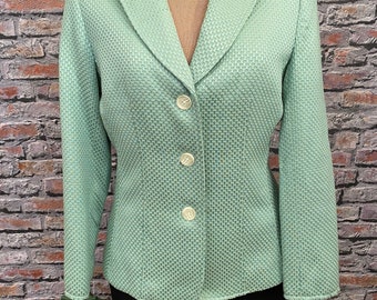 Pode incluir: Um blazer verde menta com uma trama texturizada e quatro botões brancos. O blazer tem um colarinho clássico e mangas compridas.