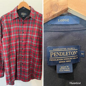 May include: Red and gray plaid flannel shirt with a long sleeve, button-up design. The shirt has a label that reads "Pendleton Woolen Mills Since 1863" and "Warranted to be a Pendleton".
