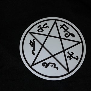 May include: A white circle with a black five-pointed star in the center. The star is surrounded by five symbols, each with a different design.