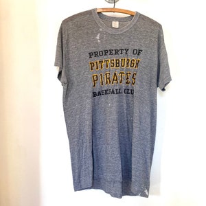 May include: Gray t-shirt with a faded, distressed look. The shirt has a black and yellow graphic that reads "PROPERTY OF PITTSBURGH PIRATES BASEBALL CLUB".