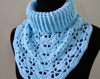 Puede incluir: Un cuello de punto de ganchillo azul claro con un delicado patrón de calado. El cuello se muestra en un maniquí negro.