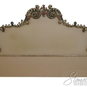 May include: A beige upholstered headboard with ornate gold-colored trim and detailing. The headboard features a curved top with floral accents and a rectangular base. The overall design is classic and elegant, suitable for a bedroom.