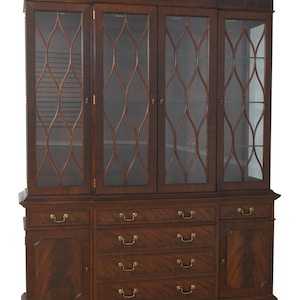 May include: A large, dark brown wooden hutch with glass-paned doors and decorative fretwork. The hutch features multiple drawers with brass hardware and a detailed crown molding. The piece is a classic furniture design.