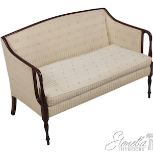 May include: A cream-colored loveseat with a striped pattern and dark wood trim. The sofa features a curved back and armrests, with a cushioned seat and back. The legs are also made of dark wood.